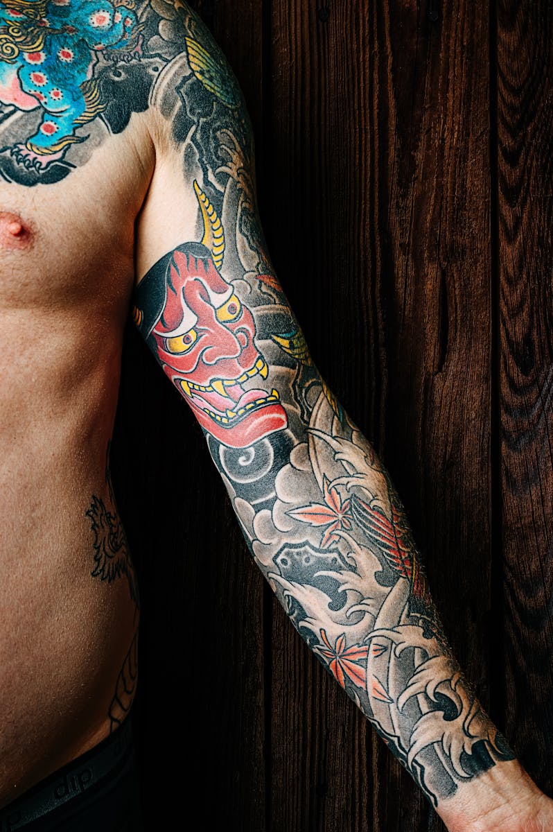 Colorful tattoo sleeve on a man's arm against a wooden background.